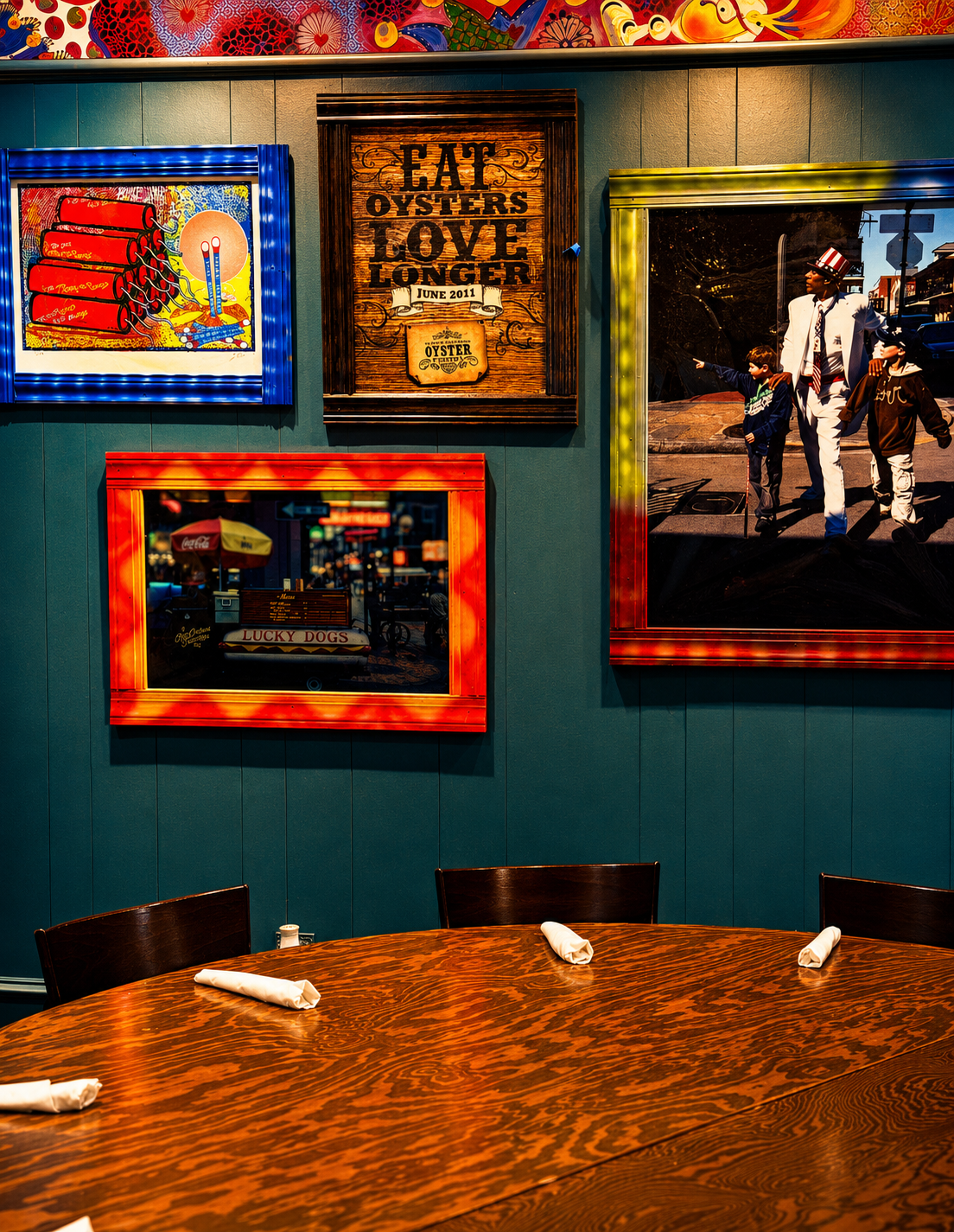 Round dining table set with napkins in the Napoleon Room, beneath framed New Orleans artwork